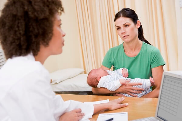 woman holding baby listening to doctor